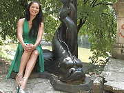 Extremely girl is sitting near the fountain in nice green dress